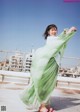 A woman in a green dress is dancing on a rooftop.