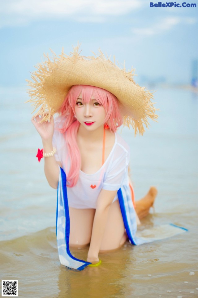 A woman in a straw hat is sitting in the water.