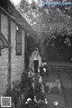 A woman standing in front of a stone building with a dog.