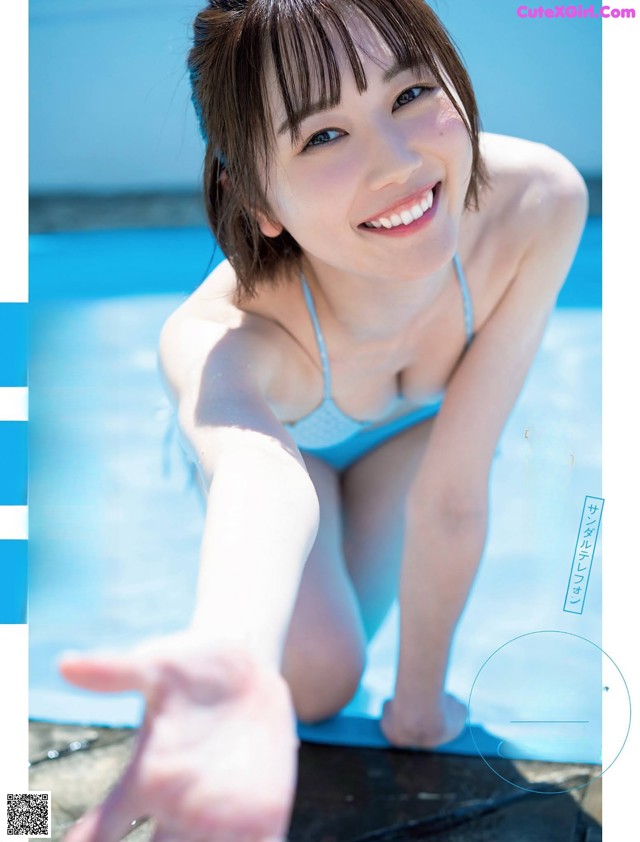 A woman in a blue bikini sitting on the edge of a pool.
