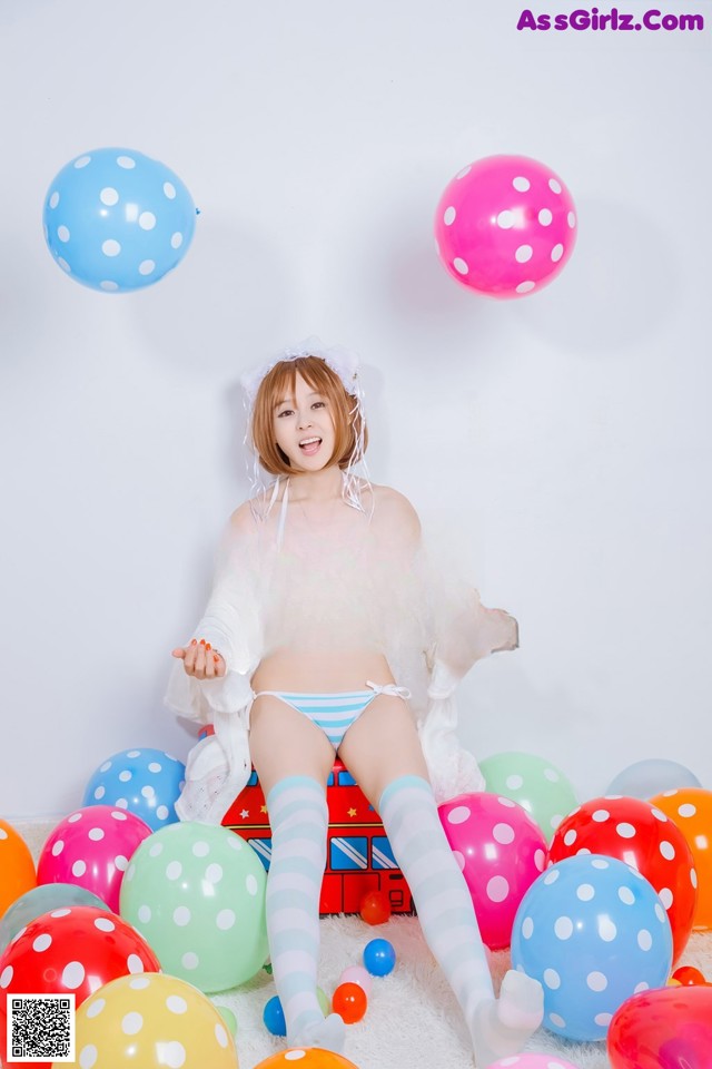 A woman sitting on top of a pile of colorful balloons.