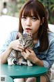 A woman sitting at a table holding a cat.