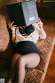 A woman laying on a couch holding a book over her head.