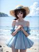 A woman in a blue dress and straw hat on the beach.