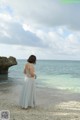 A woman standing on a beach looking out at the ocean.