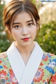 A woman in a colorful kimono poses for a picture.