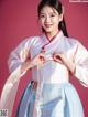 A woman in a blue and white hanbok is posing for a picture.