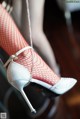 A close up of a woman's legs wearing fishnet stockings and high heels.