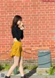 A woman walking down a sidewalk eating an ice cream cone.