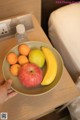 A person holding a bowl of fruit on a table.