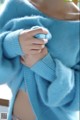 a close up of a doll wearing a blue sweater