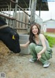 A woman kneeling down next to a black cow.