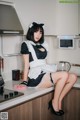 A woman in a maid outfit sitting on a kitchen counter.