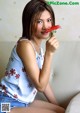 A woman sitting on a couch holding a red flower.