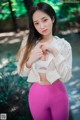 A woman in a white top and pink leggings posing for a picture.