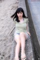 A woman sitting on a concrete wall on the beach.