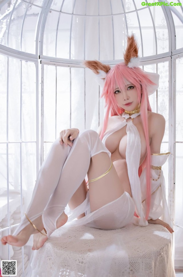 A woman with pink hair sitting on a white chair.