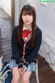 A young woman in a school uniform sitting on a chair.