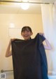 A young girl holding up a black towel in a bathroom.