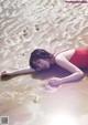 A woman in a red bathing suit laying on the beach.